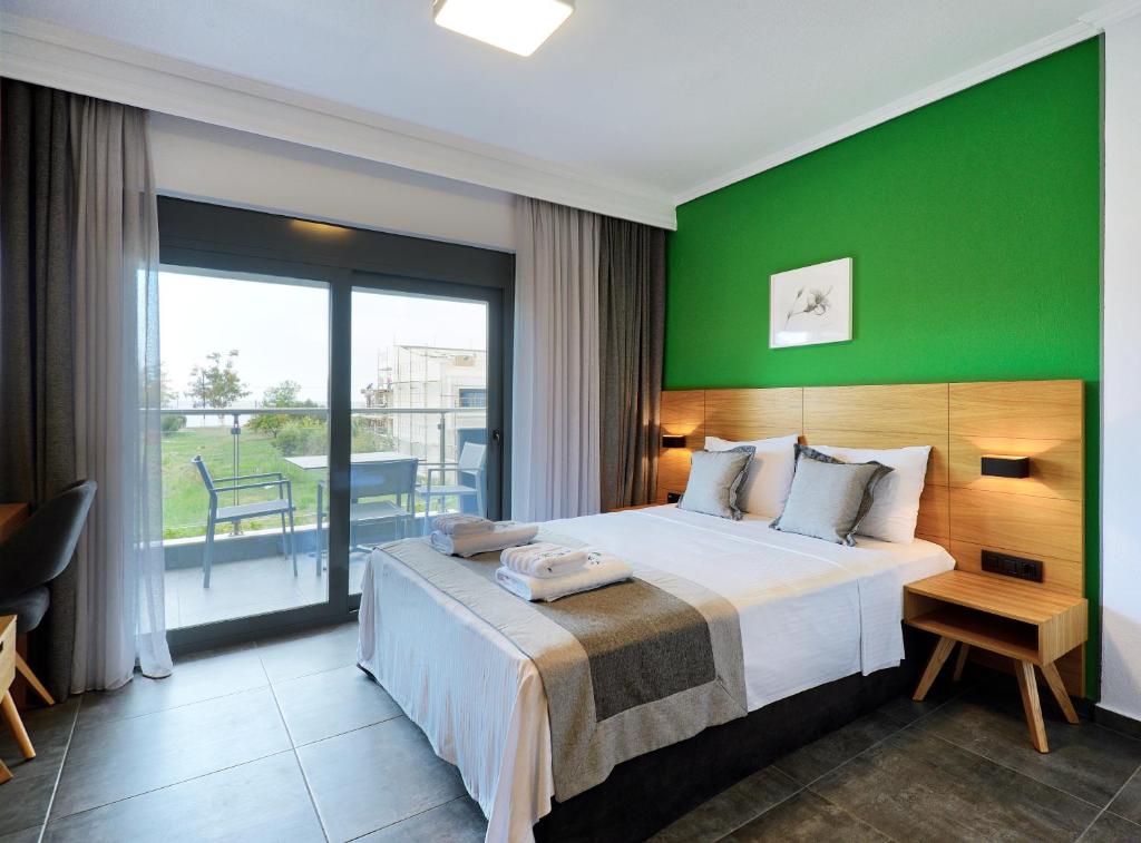 una camera da letto con un grande letto con una parete verde di Botanica Luxury Suites a Néos Marmarás