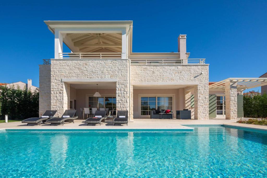 a villa with a swimming pool in front of a house at Villa Celeste by ILC (Istria Luxury Collection) in Brtonigla