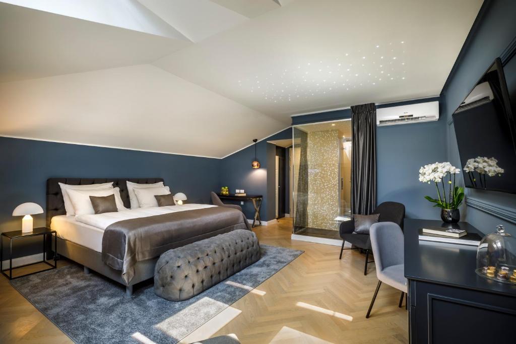 - une chambre avec des murs bleus, un lit et un canapé dans l'établissement Heritage Hotel Imperial - Liburnia, à Opatija