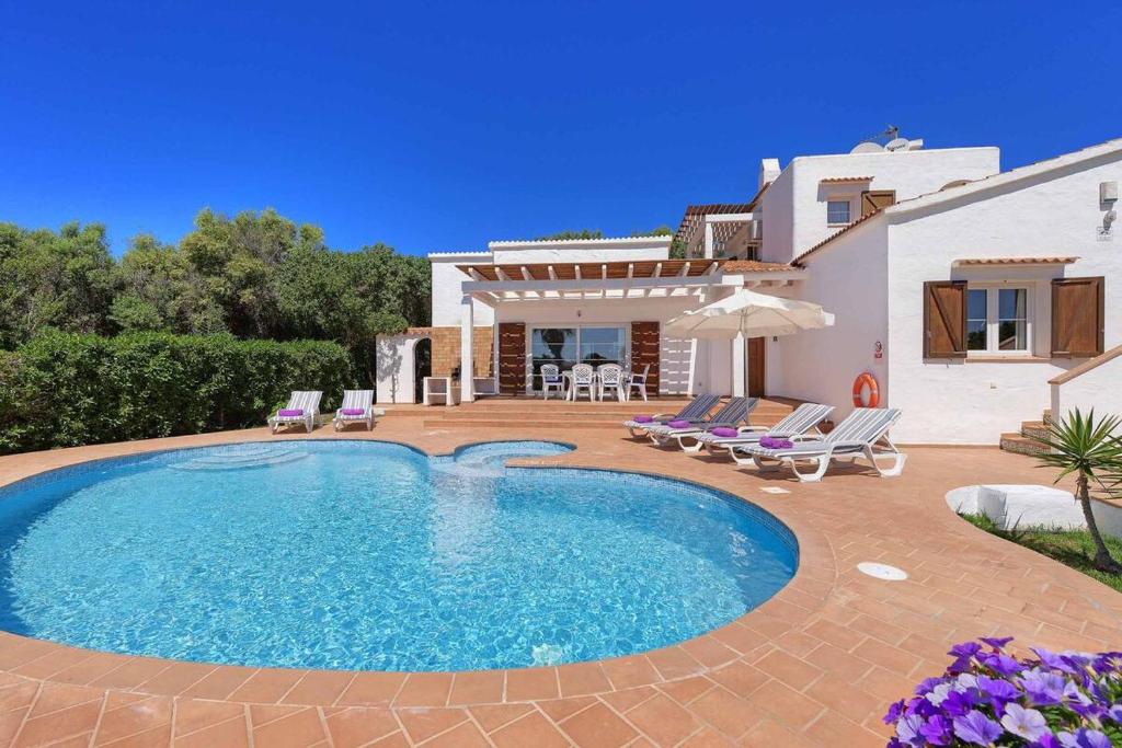 a villa with a swimming pool in front of a house at Luxury Villa in Binibeca with Jacuzzi in Sant Lluis