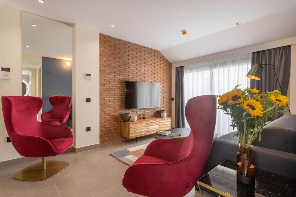 Home Art Apartments Soho في مالقة: غرفة معيشة فيها كرسيين احمر وتلفزيون