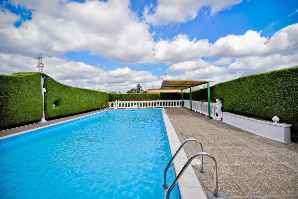 ein Pool mit grünen Hecken neben einem Gebäude in der Unterkunft I CINQUE TRULLI with Swimming Pool in Martina Franca