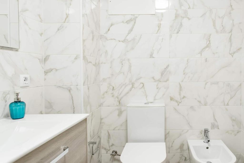 a white bathroom with a toilet and a sink at Beach House Ericeira in Ericeira