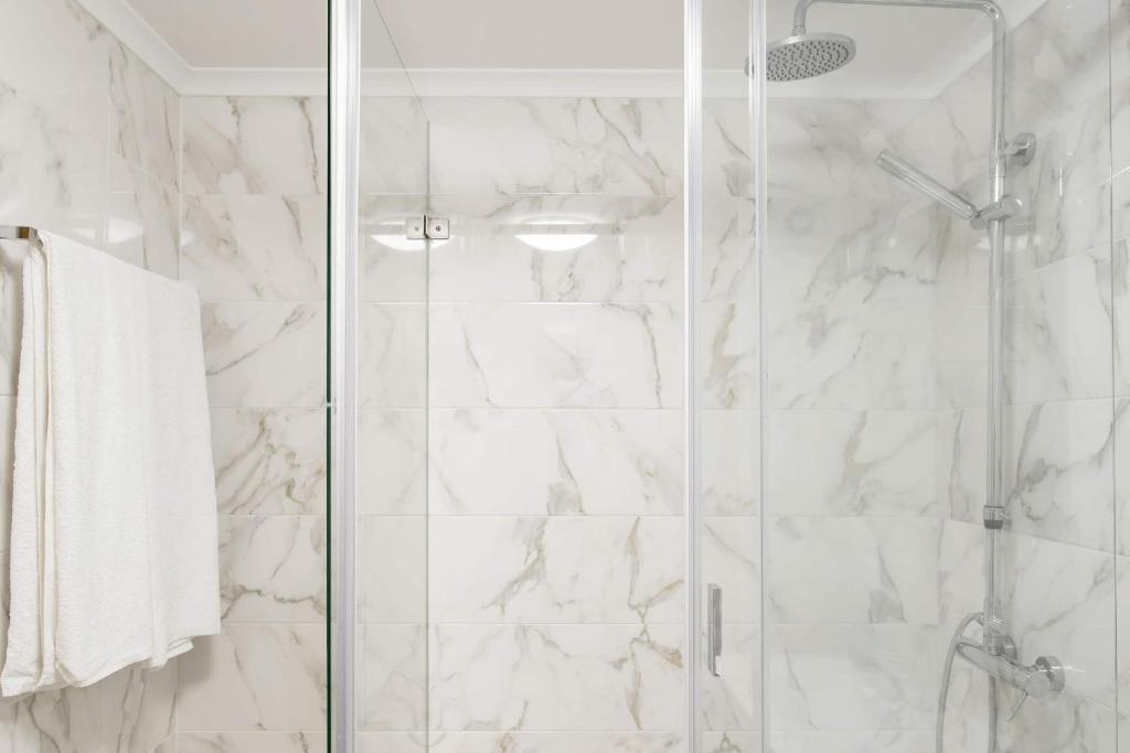 a bathroom with a shower with white marble walls at Beach House Ericeira in Ericeira