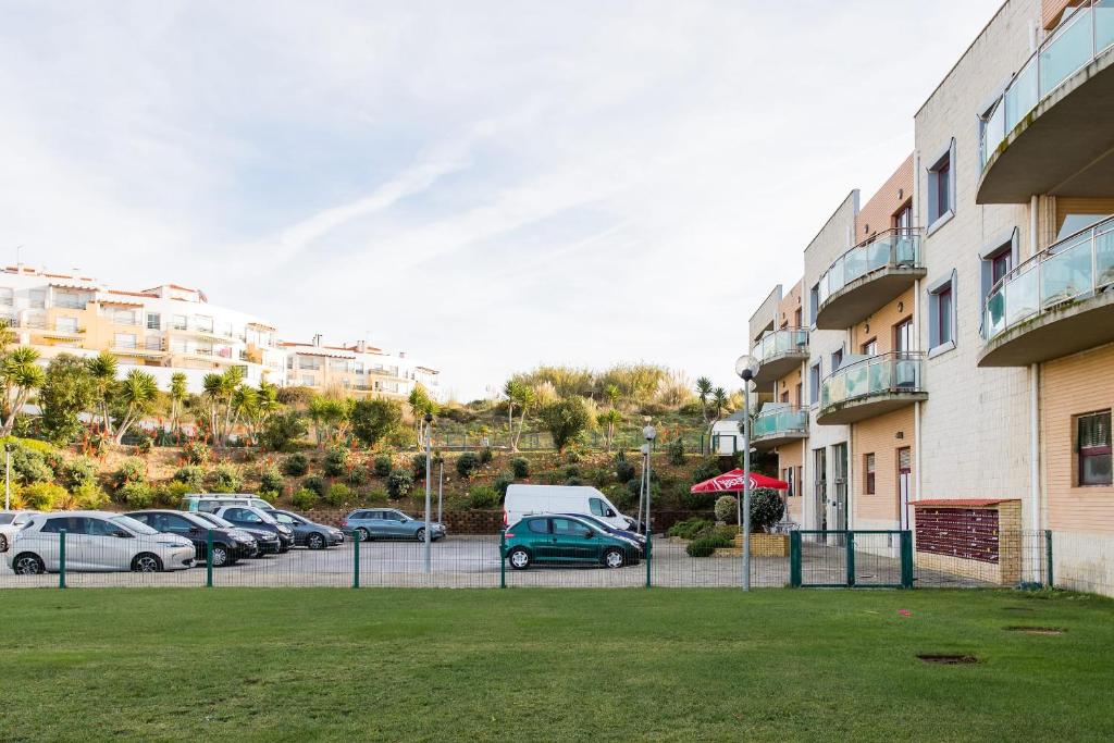 a parking lot with cars parked next to a building at Beach House Ericeira in Ericeira