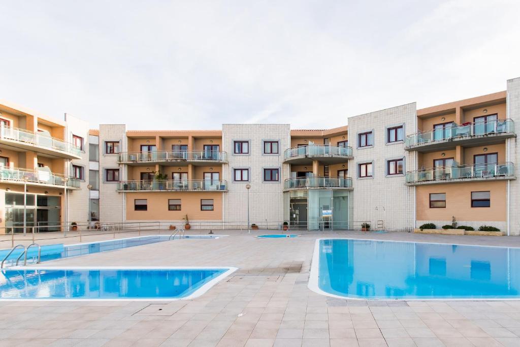 an empty swimming pool in front of apartment buildings at Beach House Ericeira in Ericeira