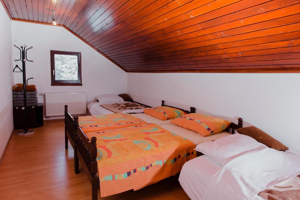 Dos camas en una habitación con techo de madera. en Planinska kuća Munika, en Risovac