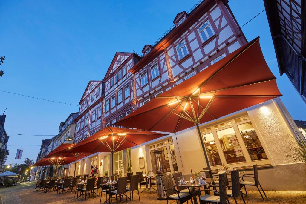 un restaurante con mesas y sombrillas frente a un edificio en Hotel Schlemmer, en Montabaur