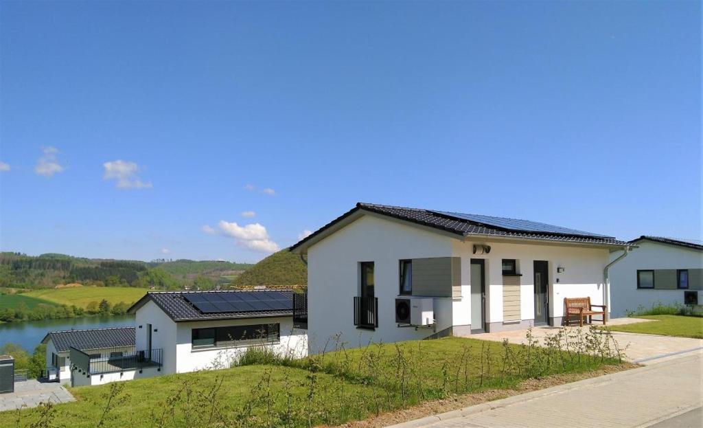 una casa blanca con ventanas negras y un cuerpo de agua en Sonnenweg 17, en Diemelsee