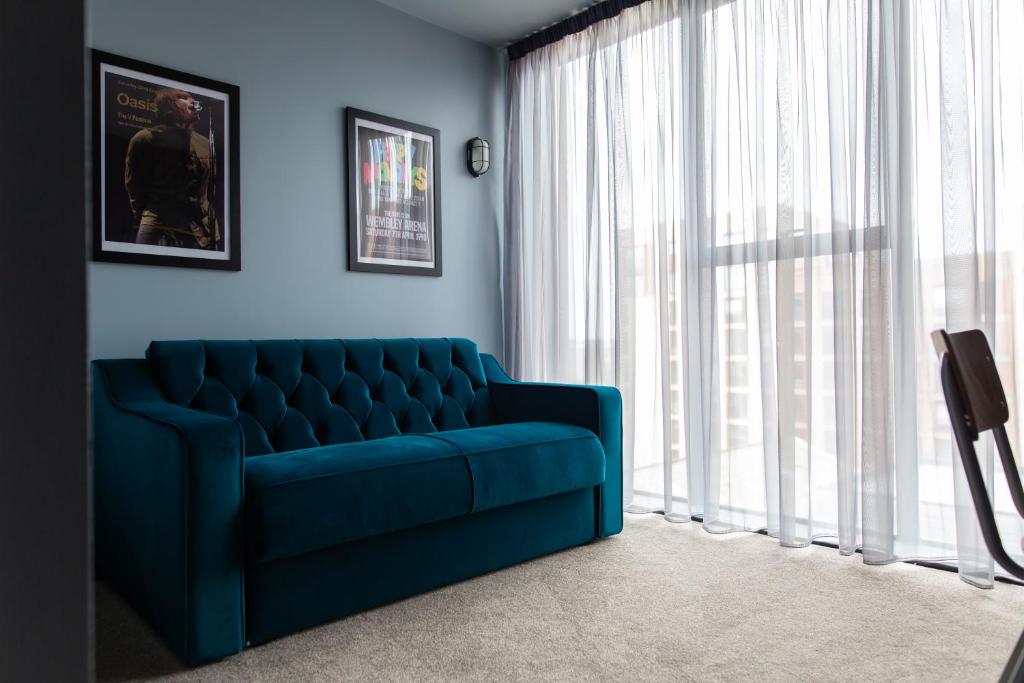 ein blaues Sofa im Wohnzimmer mit Fenster in der Unterkunft The Baltic Hotel in Liverpool