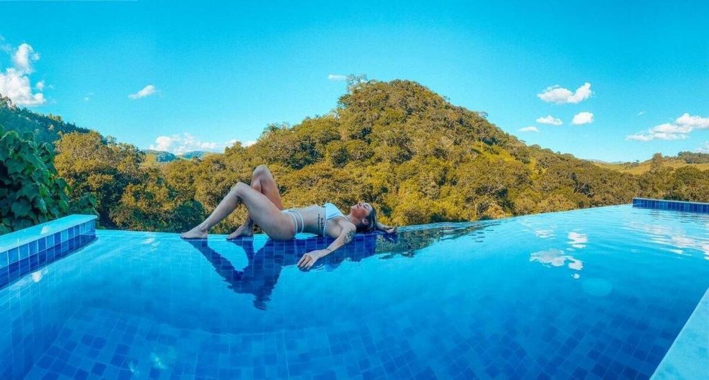 a woman laying in the water in a swimming pool at Chalé do Lago super Luxo in Cunha