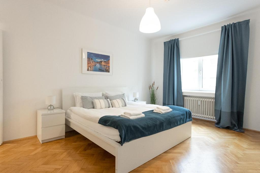 una camera bianca con un grande letto con tende blu di City Center Operastreet Apartment "Italy" a Vienna