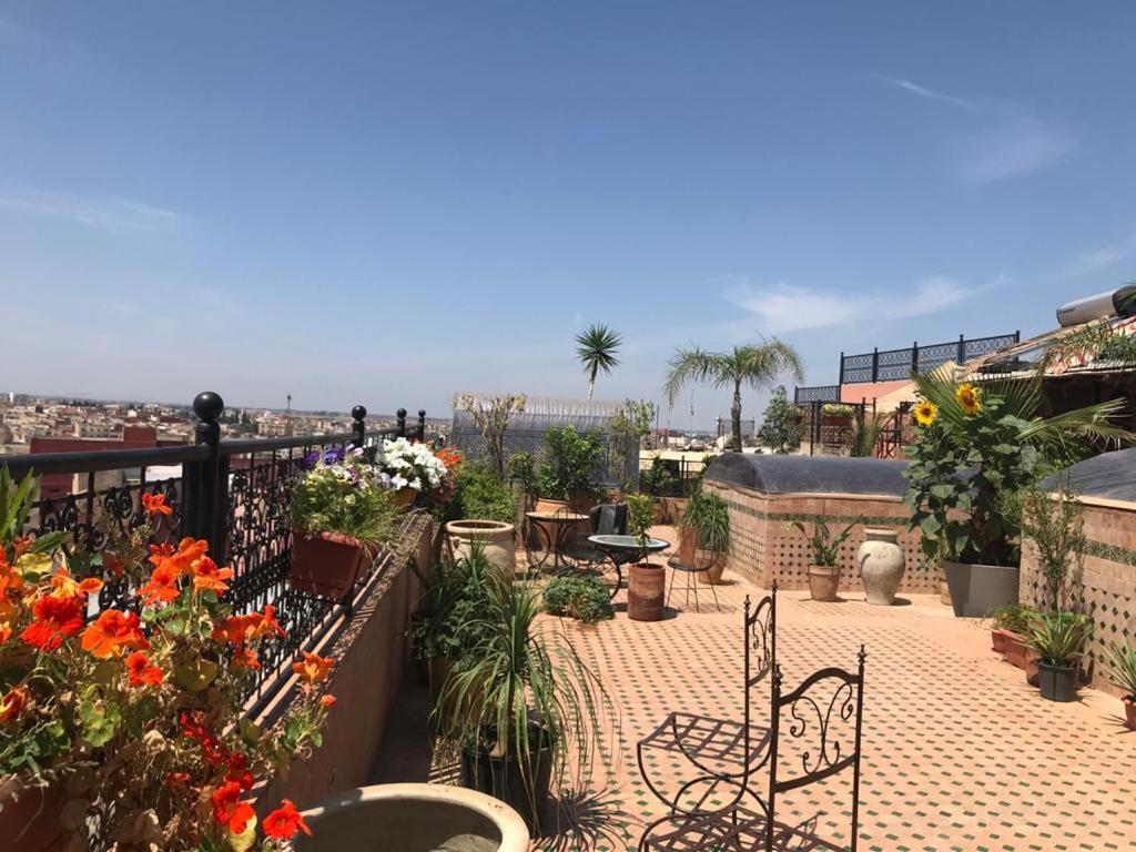 a balcony with a table and chairs and flowers at Riad le petit ksar in Meknès