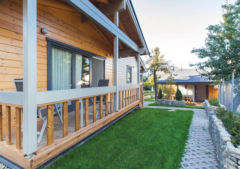 Cette maison en bois dispose d'une terrasse couverte et d'herbe verte. dans l'établissement Estudios Galende, à Galende