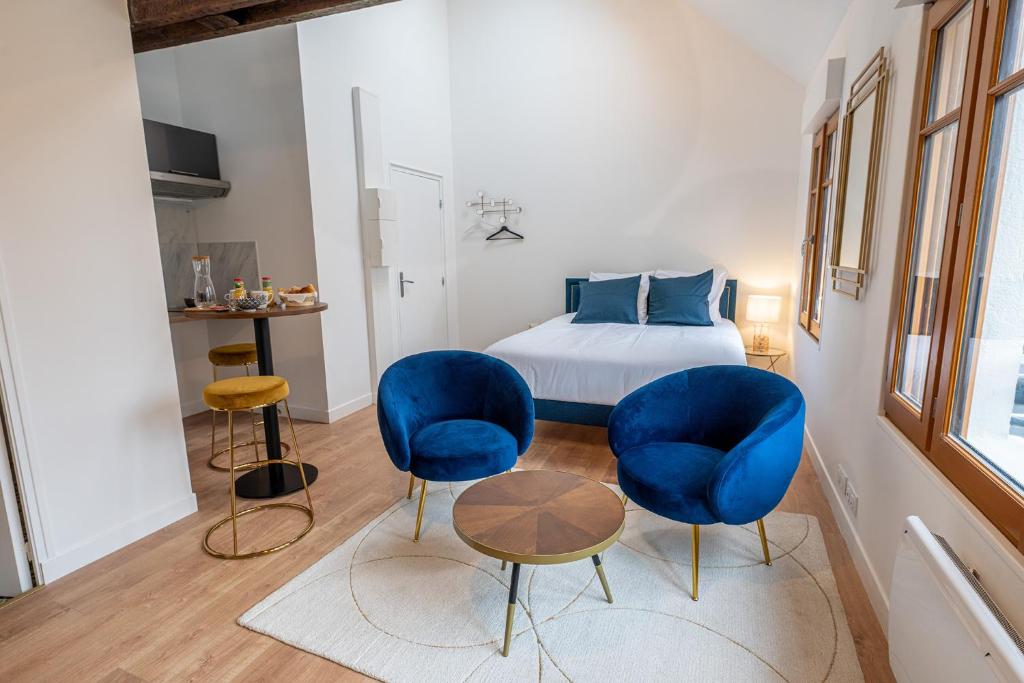 a bedroom with two blue chairs and a bed at Le Magnifique Appart'Hotel Le Gatsby in Saint-Quentin