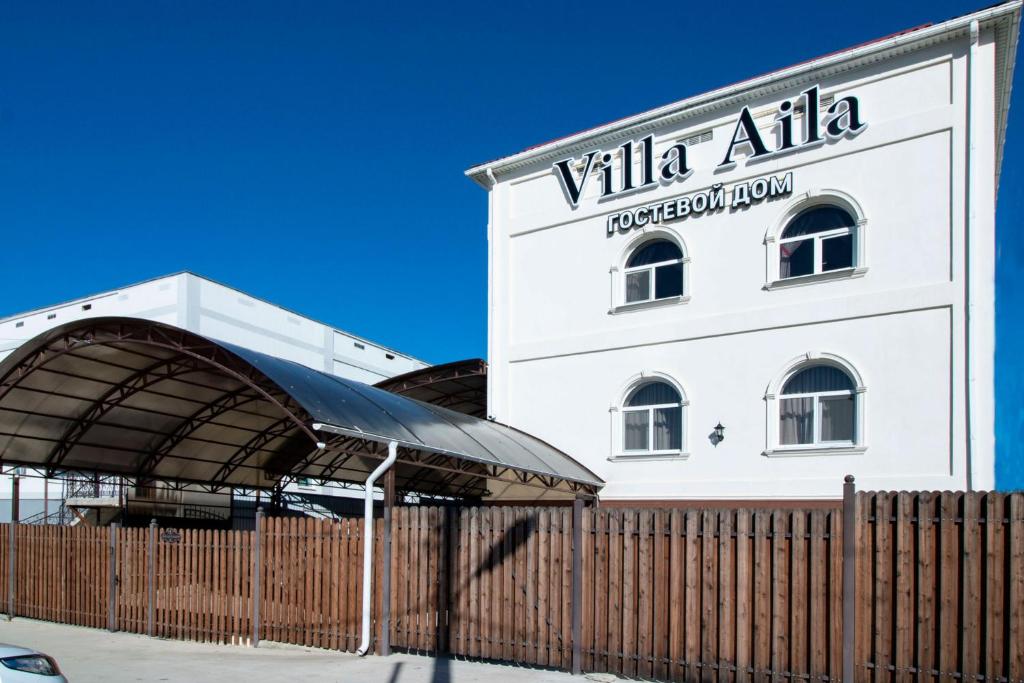 a white building with a fence in front of it at Гостевой дом Villa Aila in Mineralnie Vody