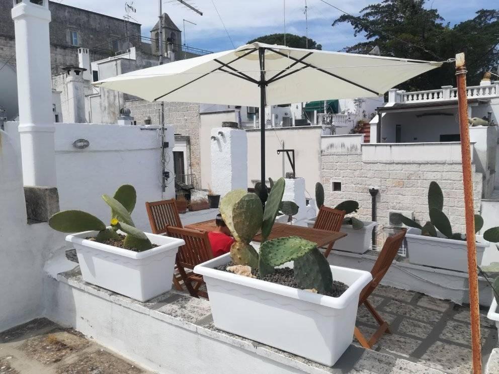 a patio with a table and chairs and an umbrella at Vico Anglani Guest House in Ostuni