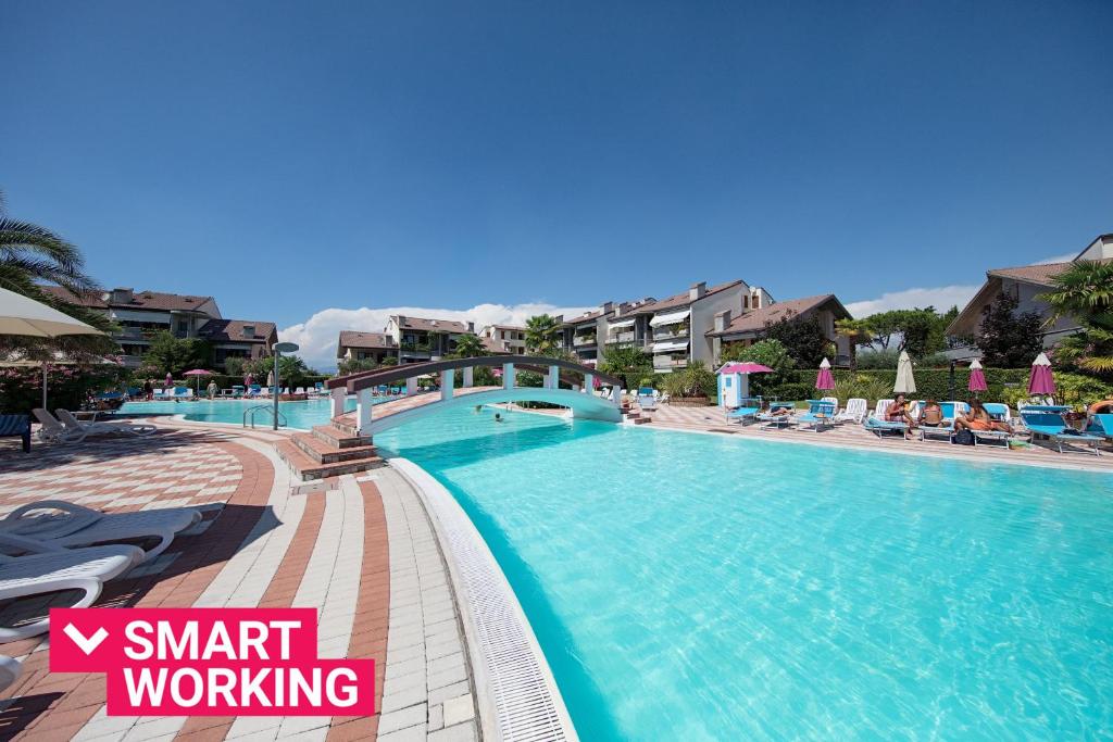 une grande piscine avec des chaises et des parasols dans l'établissement I Ciliegi 1-09 con piscina by Wonderful Italy, à Desenzano del Garda