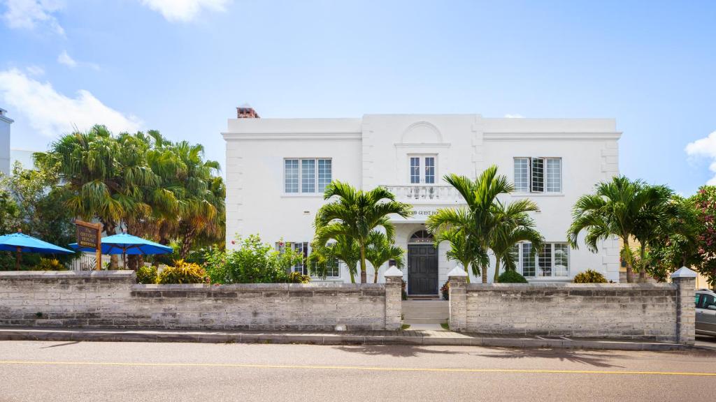 a white building with palm trees in front of a street at Oxford House in Hamilton