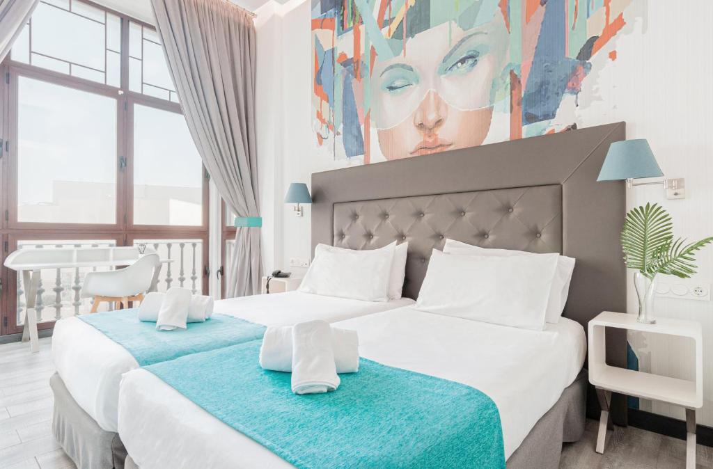 休達的住宿－Oh Nice Revellin Ceuta，卧室内的两张床,墙上有绘画作品