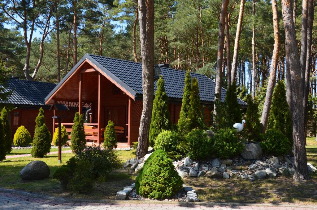 una cabaña en el bosque con árboles y arbustos en Domki Pod Wydmami 40m od plaży en Dźwirzyno