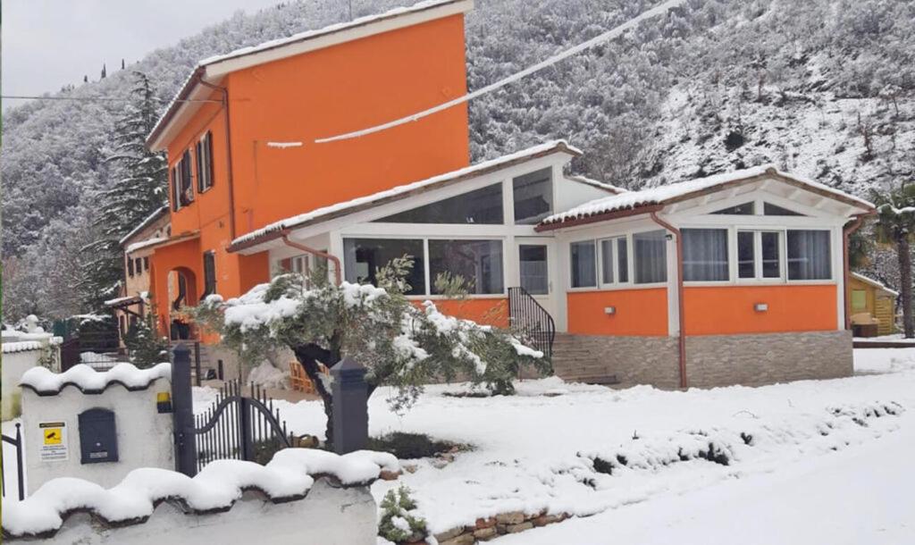 una casa naranja con nieve delante en La Meridiana, en Frontone