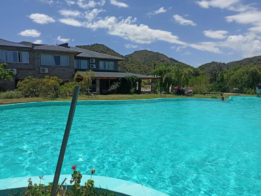 a swimming pool with blue water in front of a house at Posada El Antiguo Refugio potrero de los funes in Potrero de los Funes