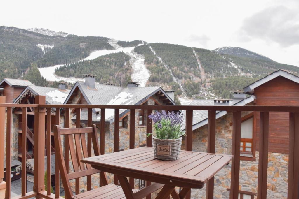 a wooden table with a potted plant on a balcony at Apartament Ninot Bonito apartamento con vistas a la X de Grandvalira in El Tarter