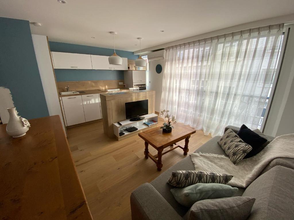 ein Wohnzimmer mit einem Sofa und einem Tisch in der Unterkunft Studio 30 M2 Hyper centre, Neuf, Parking Gratuit, 3 Étoiles in Cannes