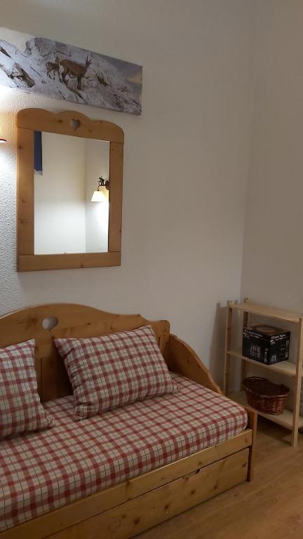 - une chambre avec un lit en bois et un miroir dans l'établissement studio, à Tignes