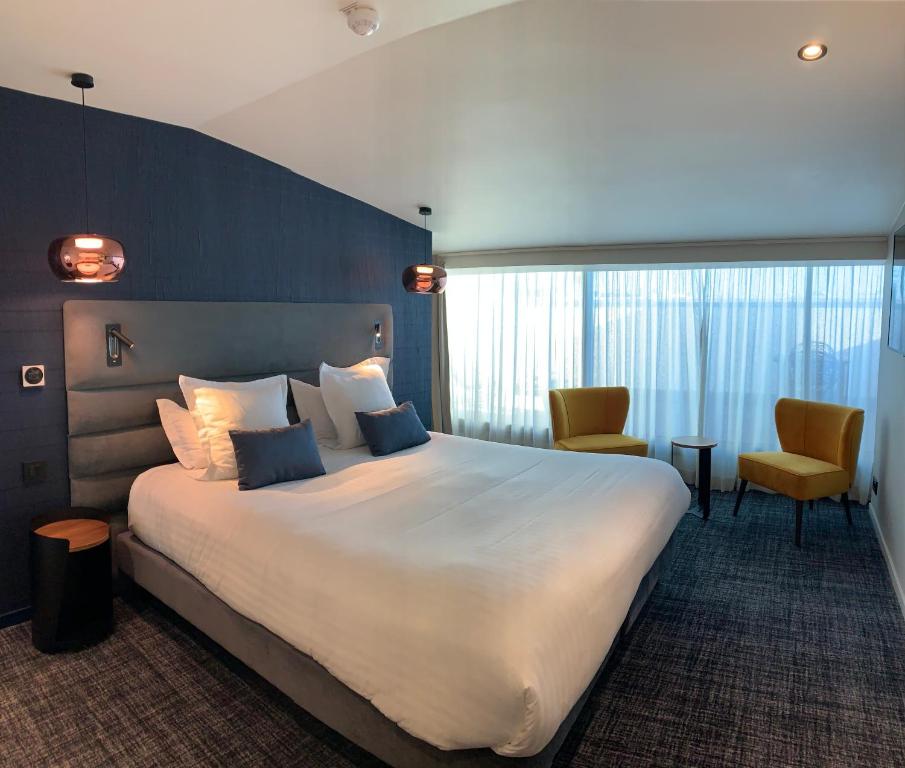ボルドーにあるHôtel La Maison Bord'eauxの大きなベッドと椅子2脚が備わるホテルルームです。