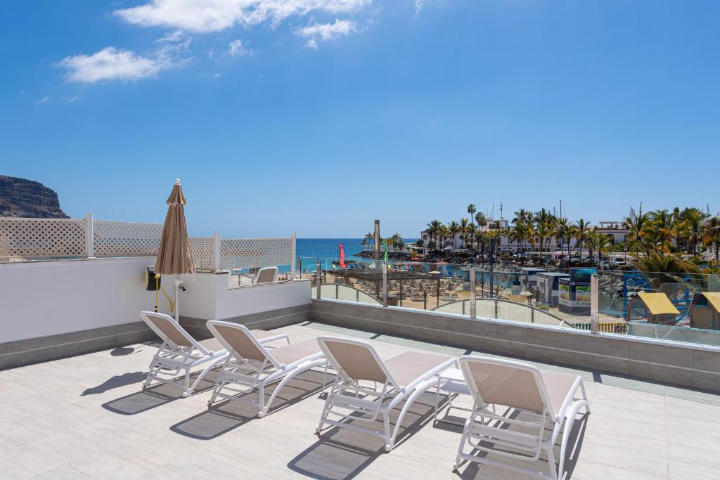 a patio with chairs and a view of the beach at BLUE SEA II - FRONT BEACH in Puerto de Mogán