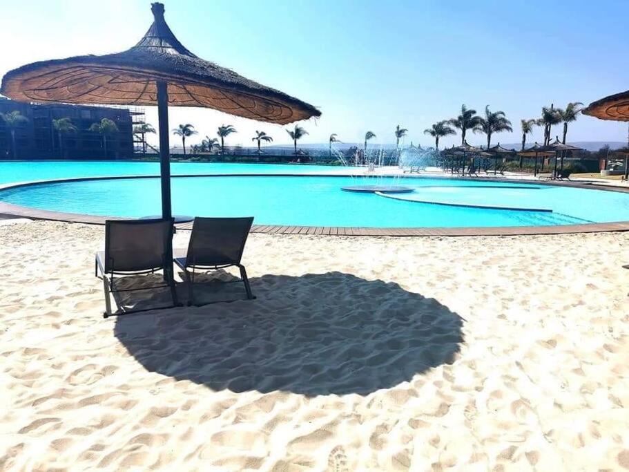 two chairs sitting under an umbrella on the beach at The Blyde Apartment 1287 in Pretoria