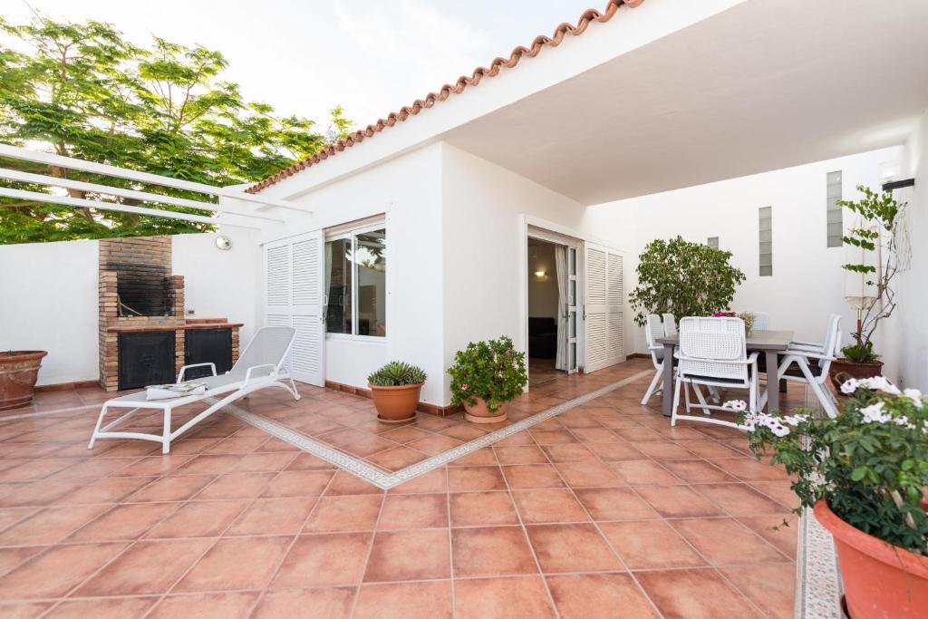 a patio with white chairs and a table at House Relax&Paradise in Maspalomas
