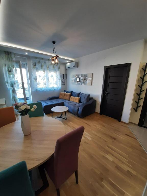 ein Wohnzimmer mit einem blauen Sofa und einem Tisch in der Unterkunft Laura Apartment in Novi Sad