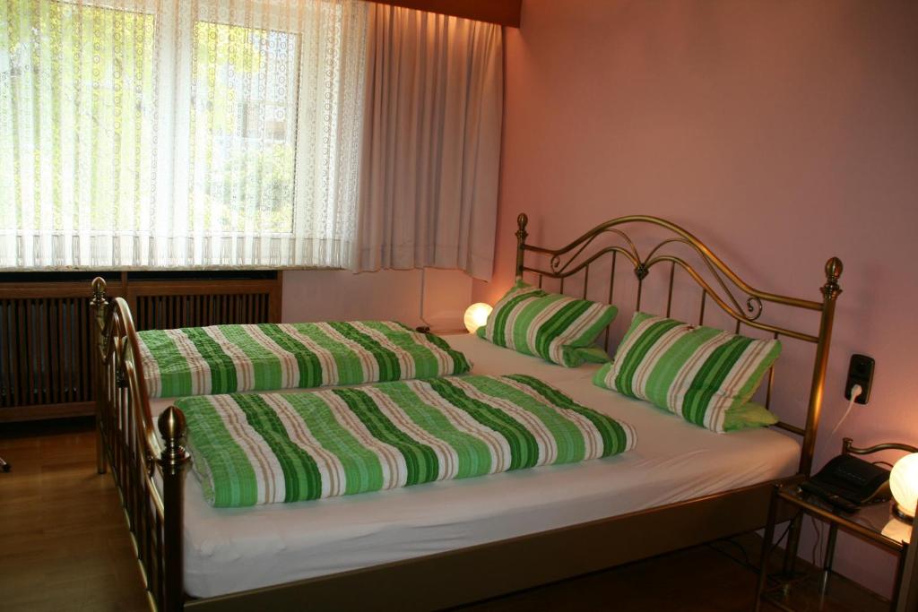 un letto con cuscini verdi e bianchi e una finestra di Aparthotel im Brauhausviertel ad Amburgo