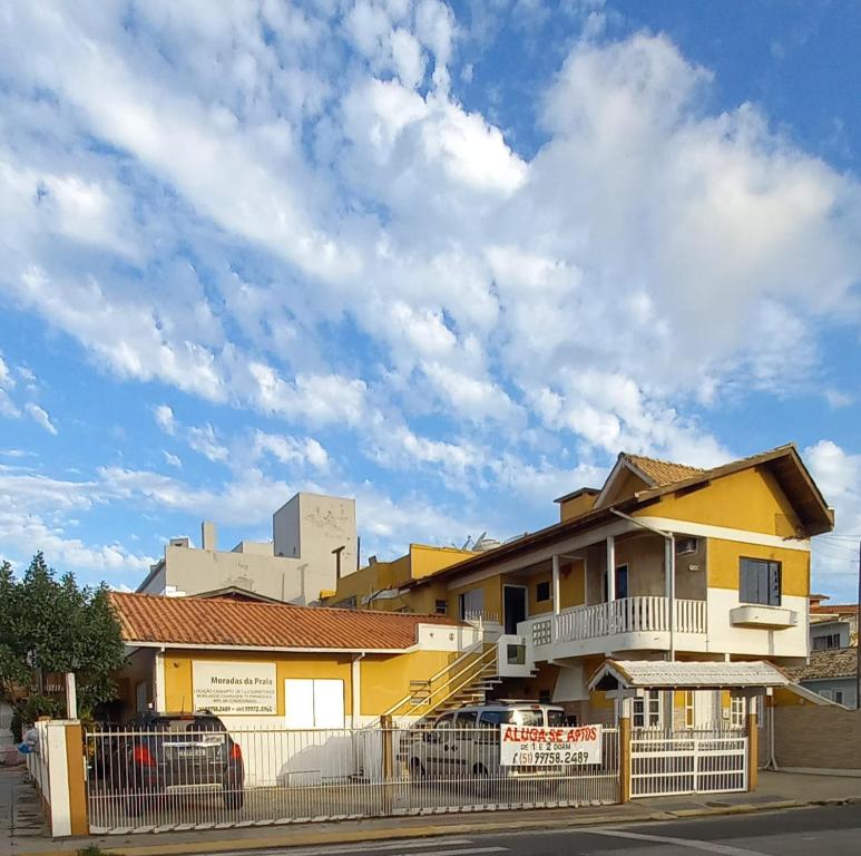 una casa amarilla con una valla delante de ella en Pousada Moradas da Praia en Garopaba