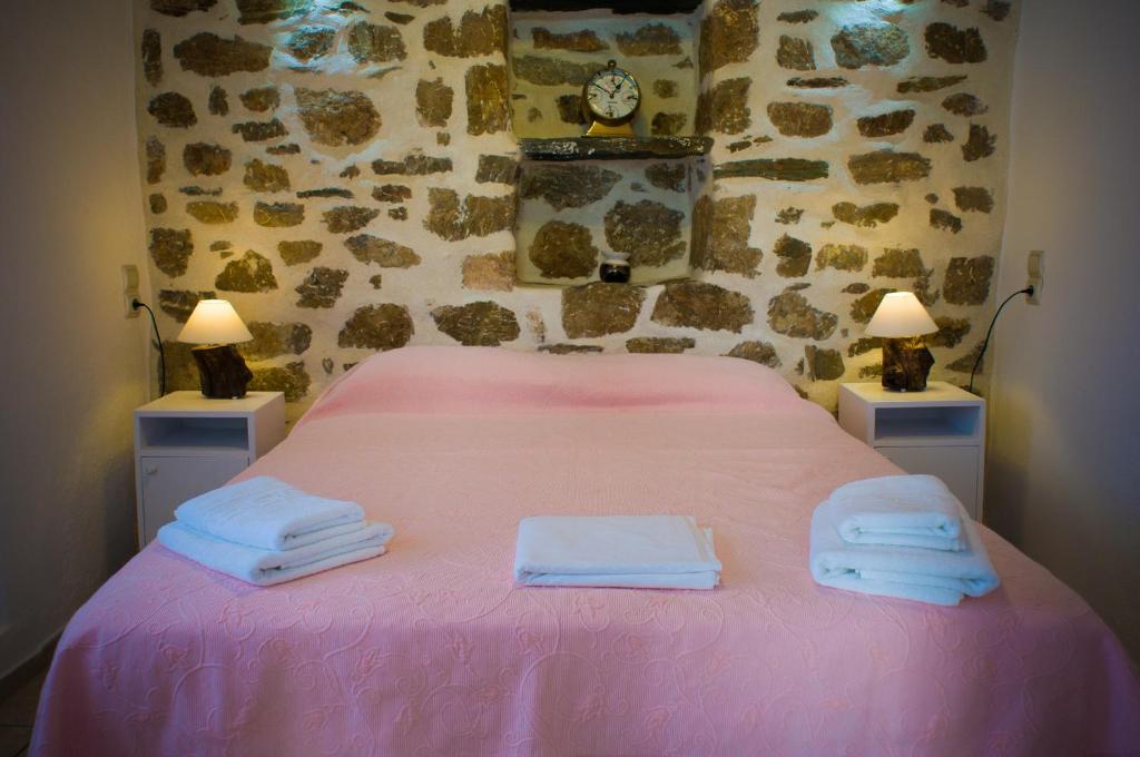 a bedroom with a pink bed with towels on it at Κymanemi Folegandros in Agali