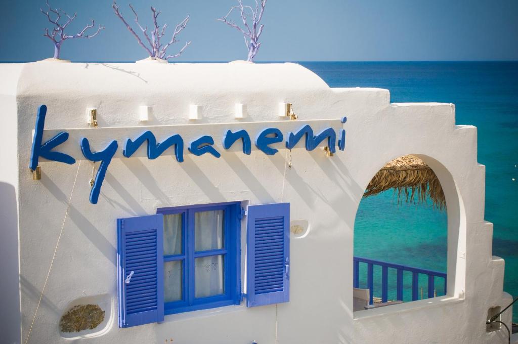 a white building with blue windows and the ocean at Κymanemi Folegandros in Agali