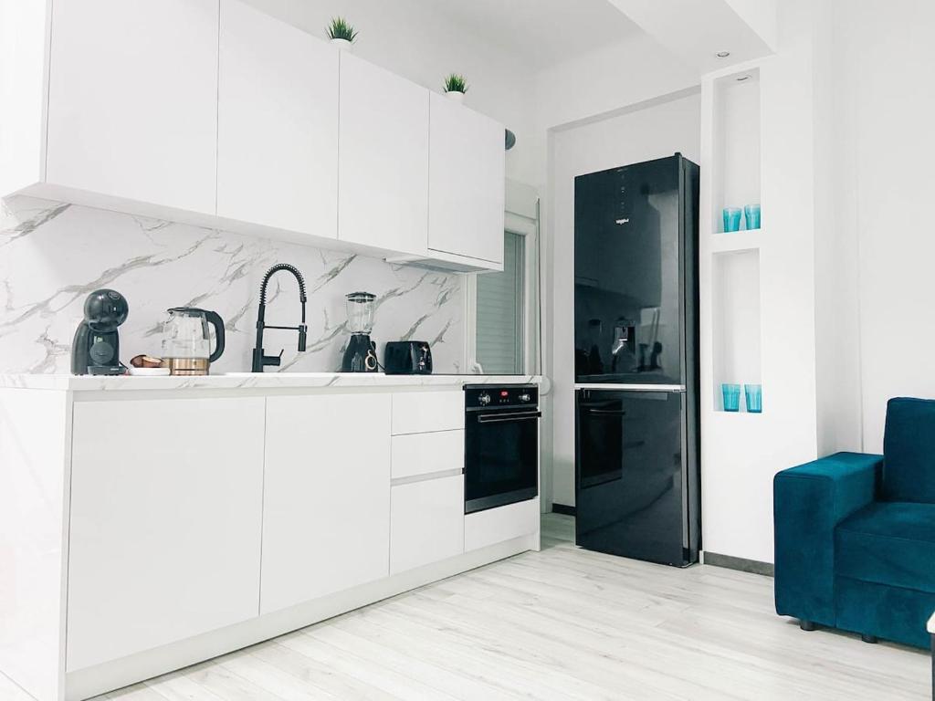 Diamond apartment في سلانيك: مطبخ فيه دواليب بيضاء وثلاجة سوداء
