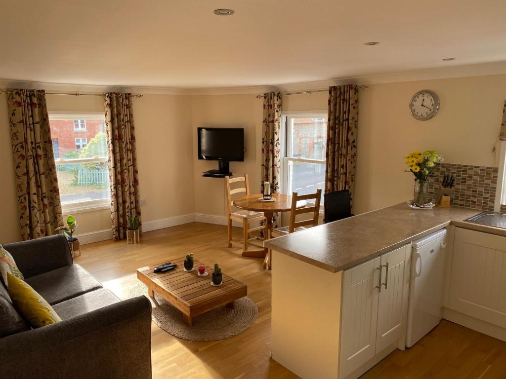 eine Küche und ein Wohnzimmer mit einem Sofa und einem Tisch in der Unterkunft Lovely apartment in beautiful coastal village in Weybourne