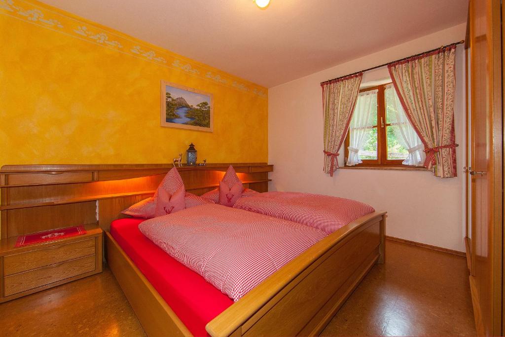 una camera con letto in legno e lenzuola rosse di Gästehaus Arnspitzblick a Scharnitz