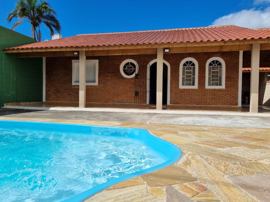 a swimming pool in front of a house at Acolhedora casa renovada - Piscina e a 100m da praia in Caraguatatuba