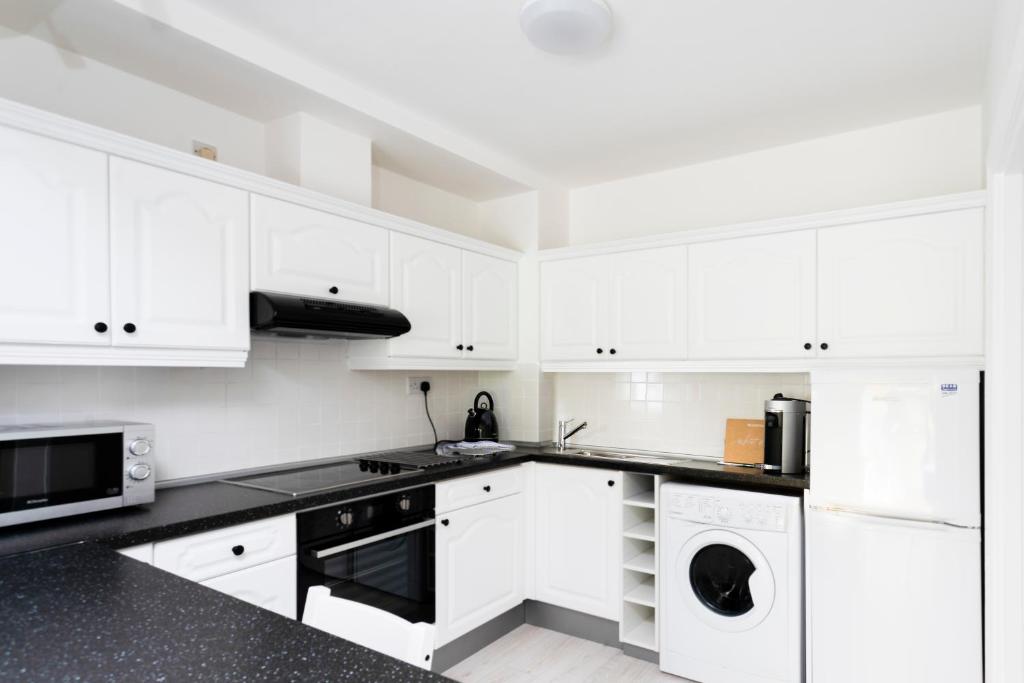 une cuisine avec des placards blancs et un comptoir noir dans l'établissement Windmill Lane 002, à Dublin
