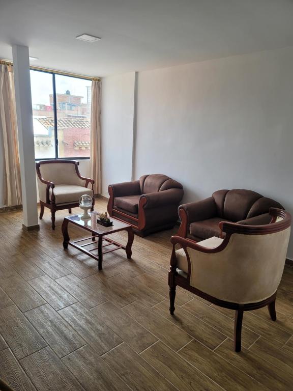 a living room with two chairs and a couch and a table at Departamentos La Estación del tren de dos habitaciones in Riobamba