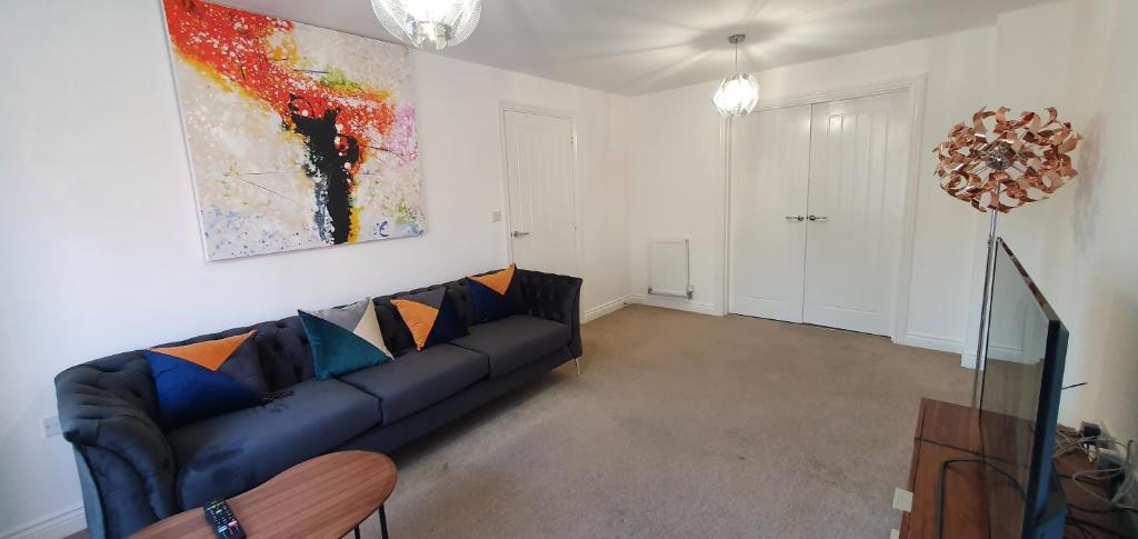 a living room with a couch and a painting on the wall at Garland Modern 4 Bedroom House with Garden & Parking in Kent