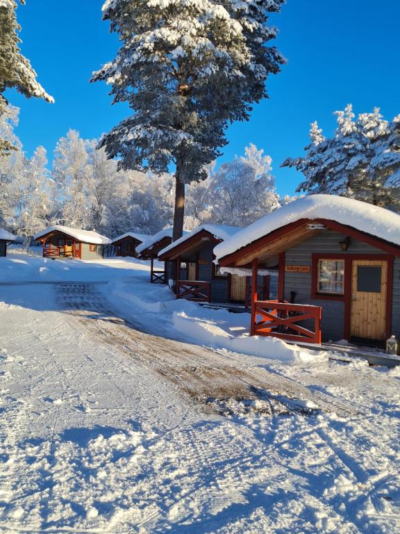 a cabin covered in snow next to a road at Sonfjällscampen in Hede