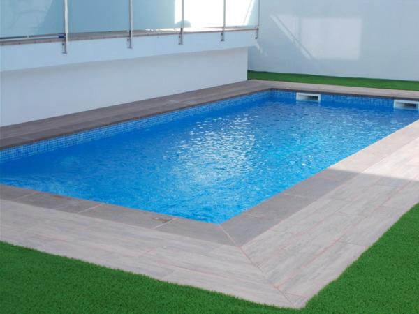 a large swimming pool in a room with green grass at Villa Jupiter con piscina privada in Cambrils