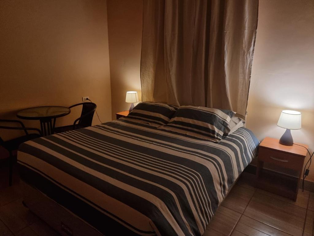 uma cama num quarto com uma mesa e dois candeeiros em Hospedaje Atitur em San Pedro de Atacama