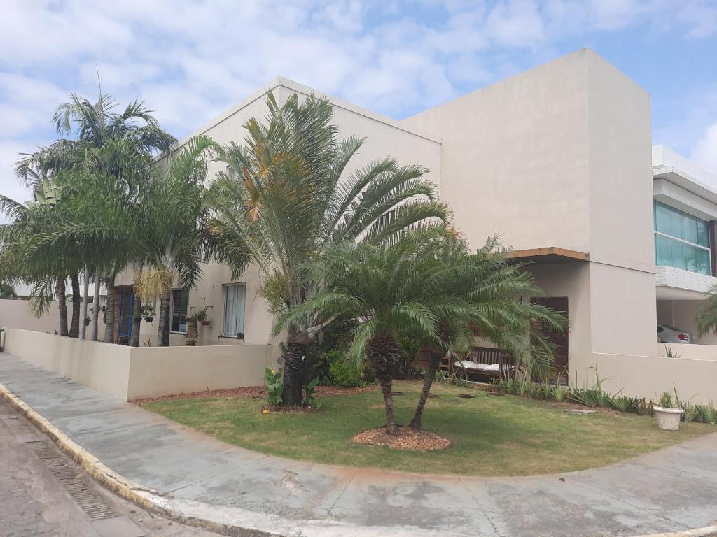 un edificio blanco con palmeras delante en Fantástica casa 4 quartos próxima a praia em condomínio fechado !, en Aracaju